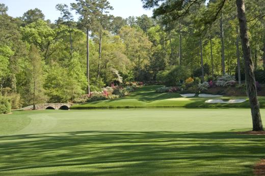 A golf course usually consists of rolling hills that are set between sparse woods.